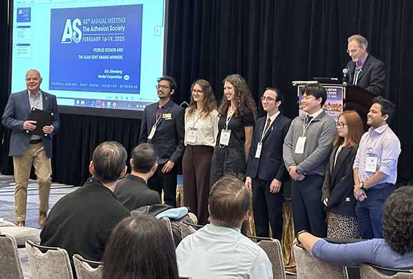 PhD students on stage lined up awaiting presentation of awards
