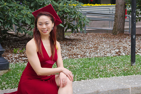 student in graduation attire sitting outside