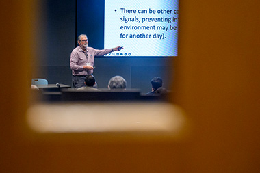 Herbert Levine, distinguished professor of physics and bioengineering, standing in front of a project giving a presentation