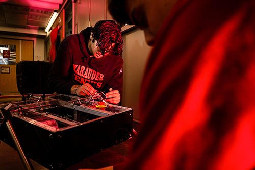 young students sits on the floor working on a robot