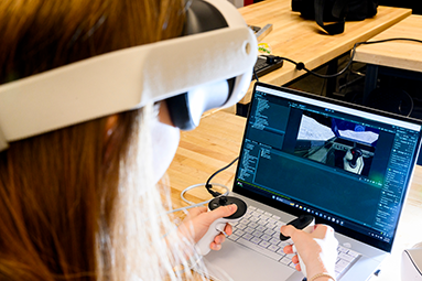 student wearing vr goggles and looking at a computer