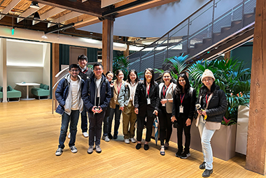 10 people standing in a line by a staircase and smiling at the camera 